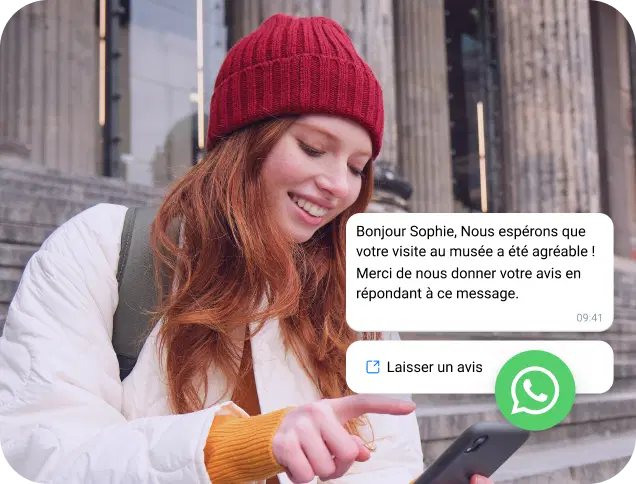 Une jeune femme avec une casquette rouge consulte un message professionnel sur WhatsApp sur son téléphone.