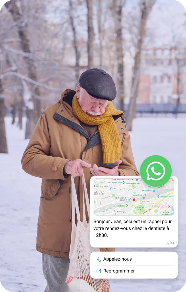 Un homme âgé sous la neige vérifie son téléphone pour obtenir des informations sur l'emplacement via un message WhatsApp professionnel.