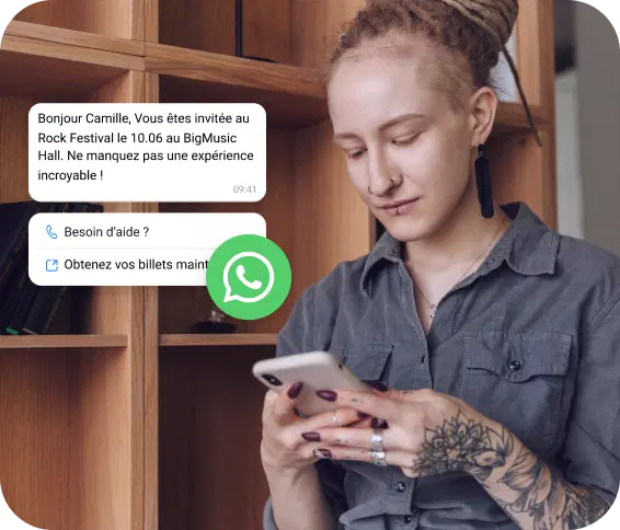Une fille tatouée regarde son téléphone pour une invitation à un festival de rock reçue sur WhatsApp.