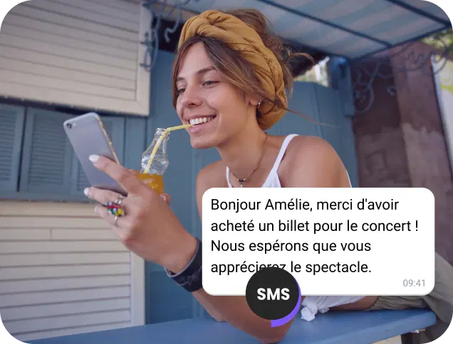 Une fille, en dégustant un jus dans la rue, vérifie la confirmation de son billet de concert reçue par SMS.