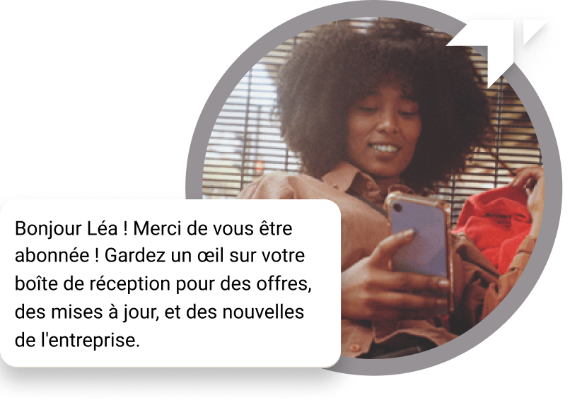 Fille aux cheveux bouclés assise par terre vérifiant son téléphone pour un message de ‘Merci’ reçu pour son abonnement