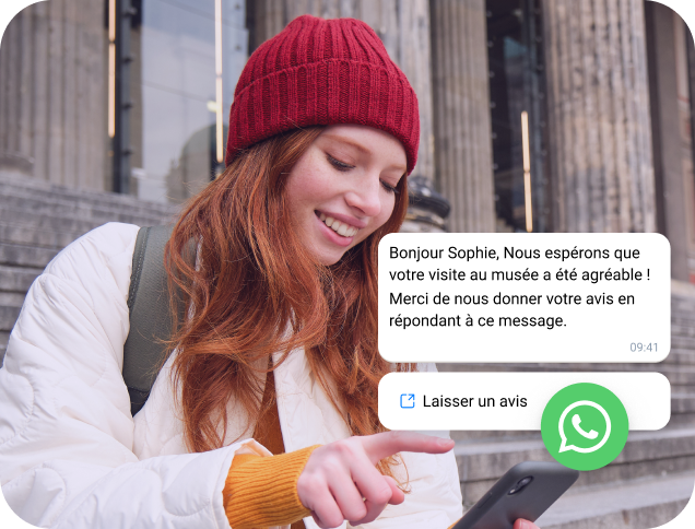 Une jeune femme en casquette rouge lit un message professionnel WhatsApp sur son téléphone dans le cadre d'une campagne marketing par SMS.